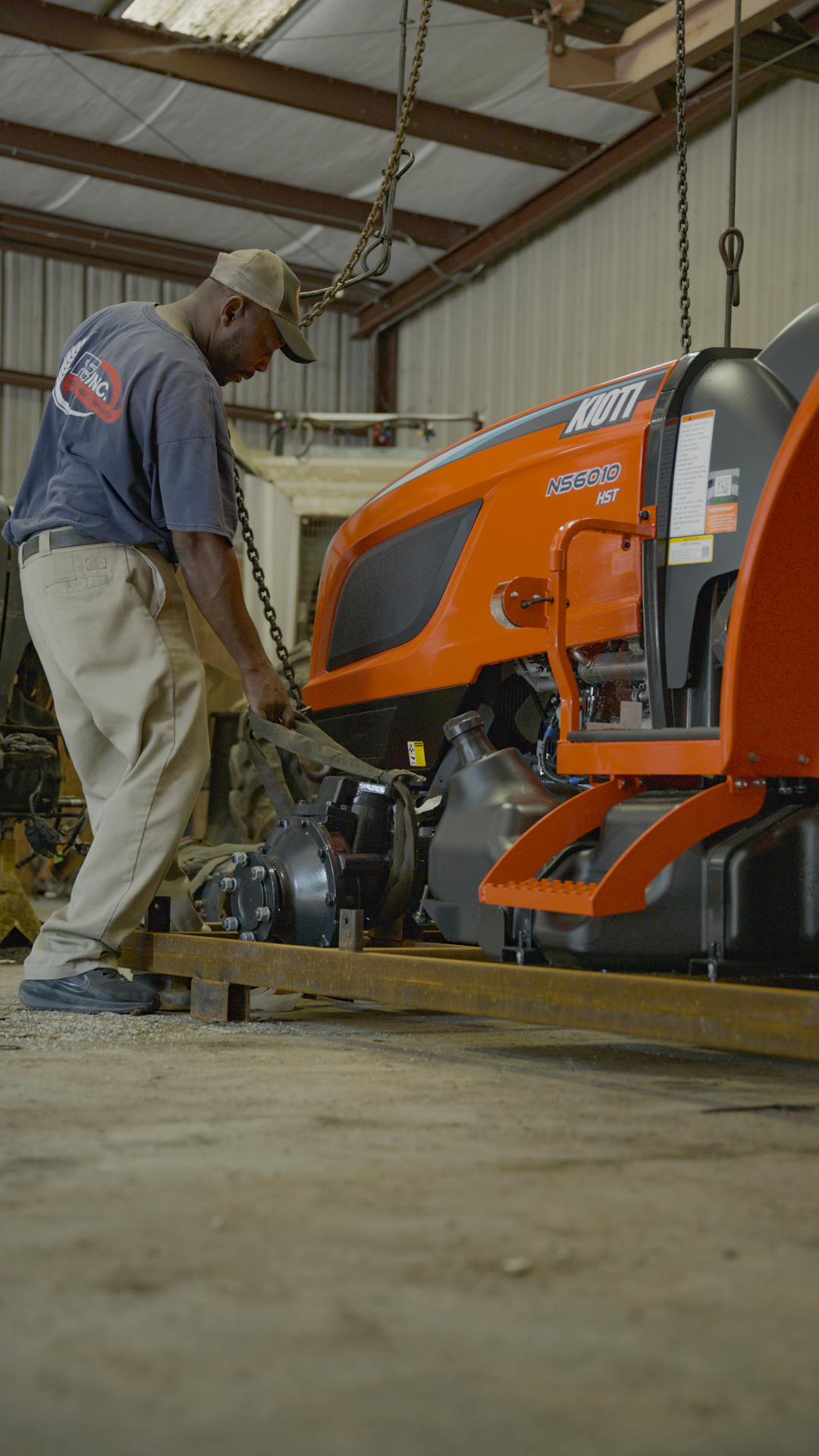 Mechanic working on a KIOTI tractor inside the Robertson Equipment shop